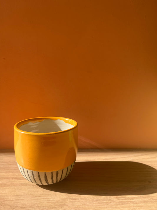 Orange ceramic cup with black line pattern
